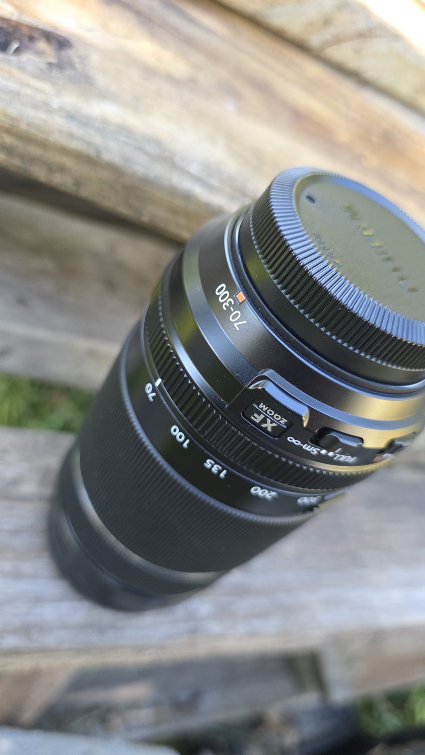 The Fujinon XF70-300mm lens on a wooden rail.