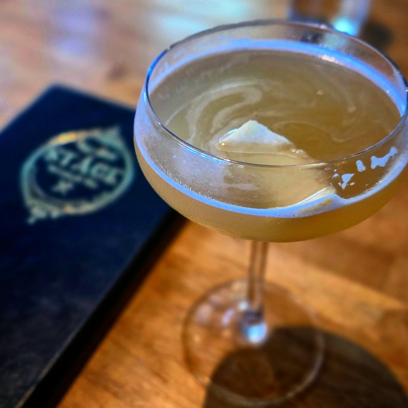 Cocktail in a coupe glass at Stäge Kitchen & Bar in Peachtree Corners, Georgia, photographed with shallow focus and warm interior light.