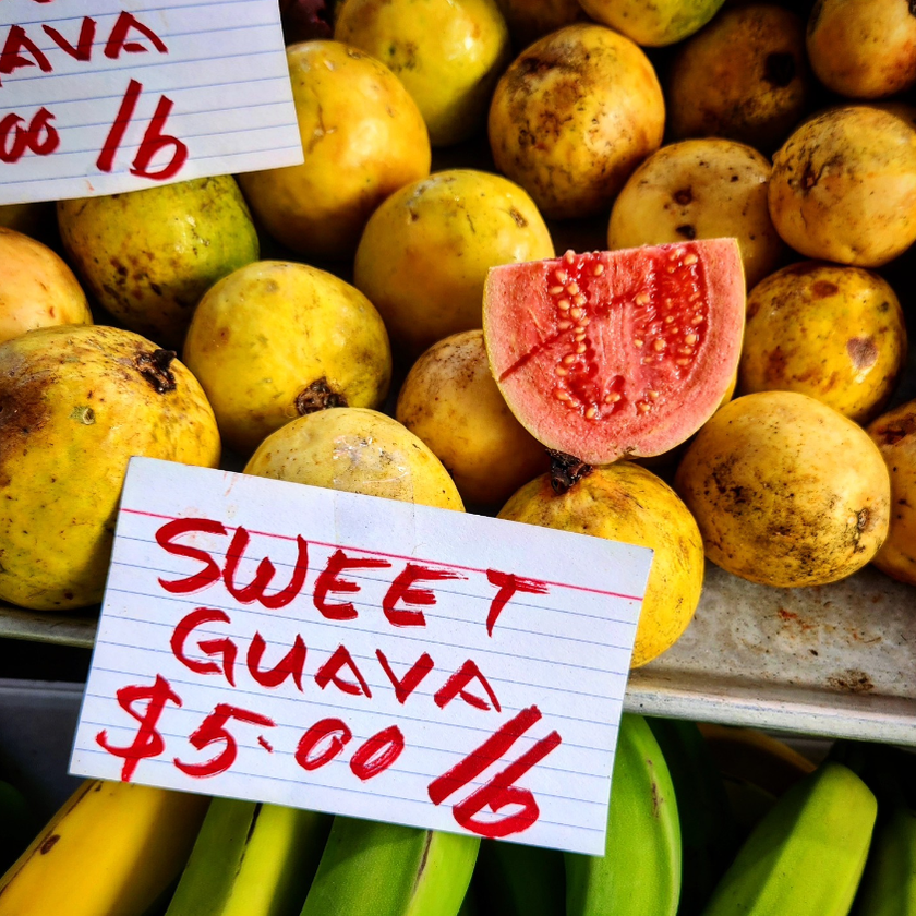 Fresh tropical fruit, including a sliced pink guava, displayed at Hilo Farmers Market on Hawaii Island.